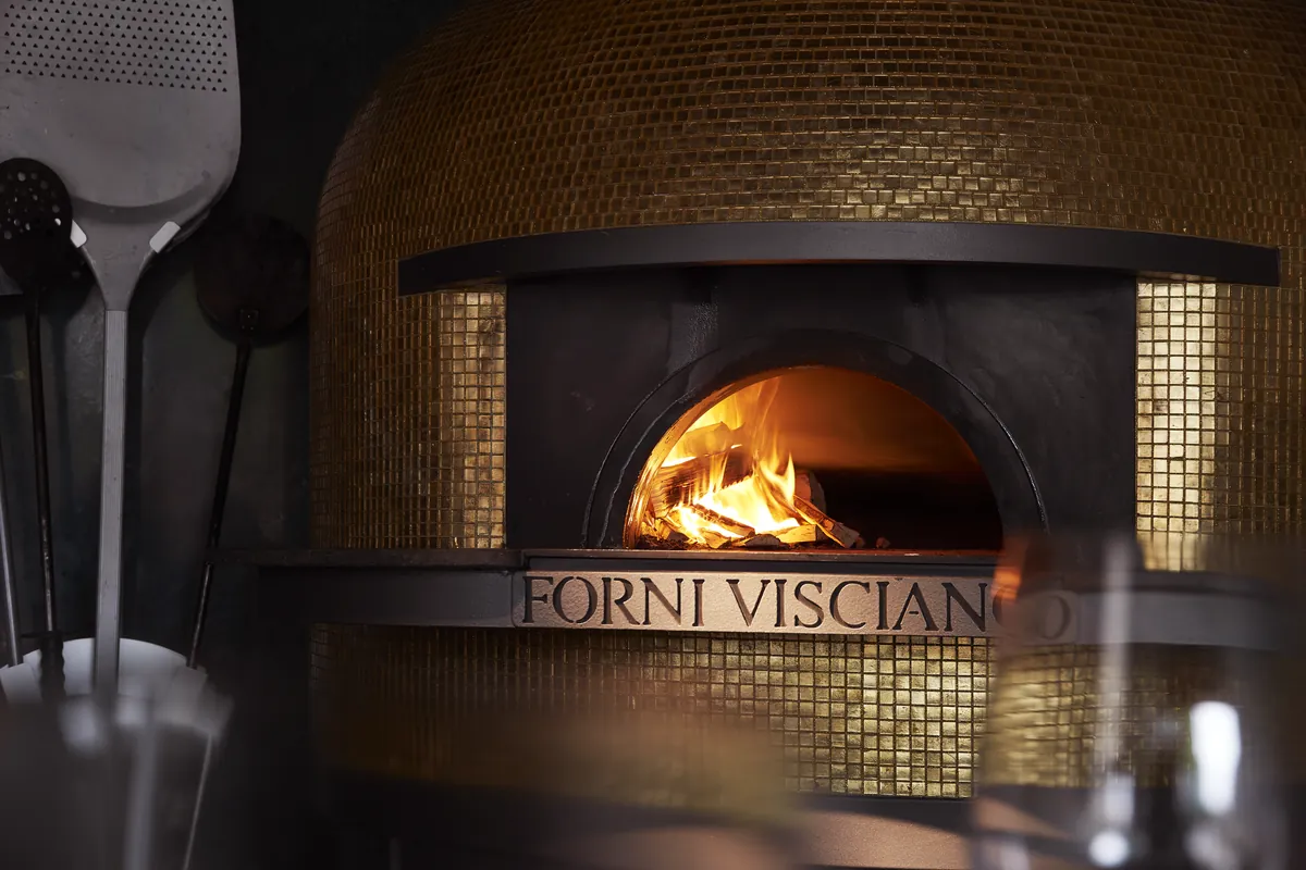 The wood fire in the gold oven, peels hanging beside it